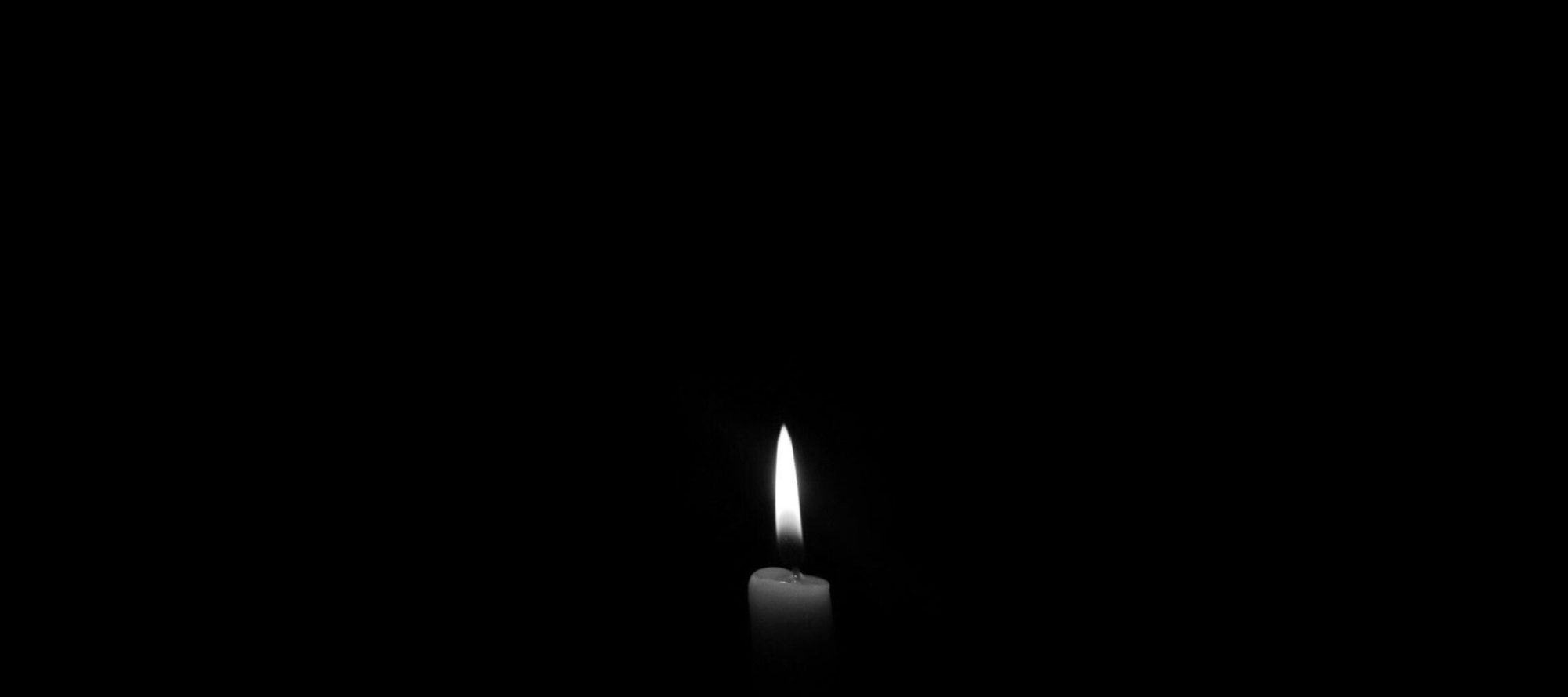 A solitary candle flame against a plain black backdrop, epitomizing simplicity and tranquility.